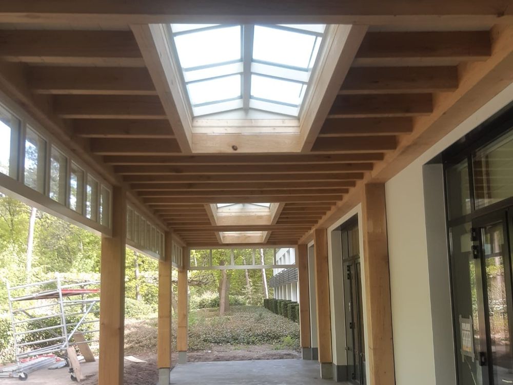 Houten overkapping met eiken balken en lichtstraten langs de gevel