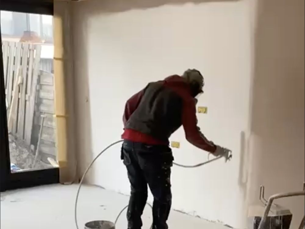 Schilder spuit een wand in een lege woonkamer